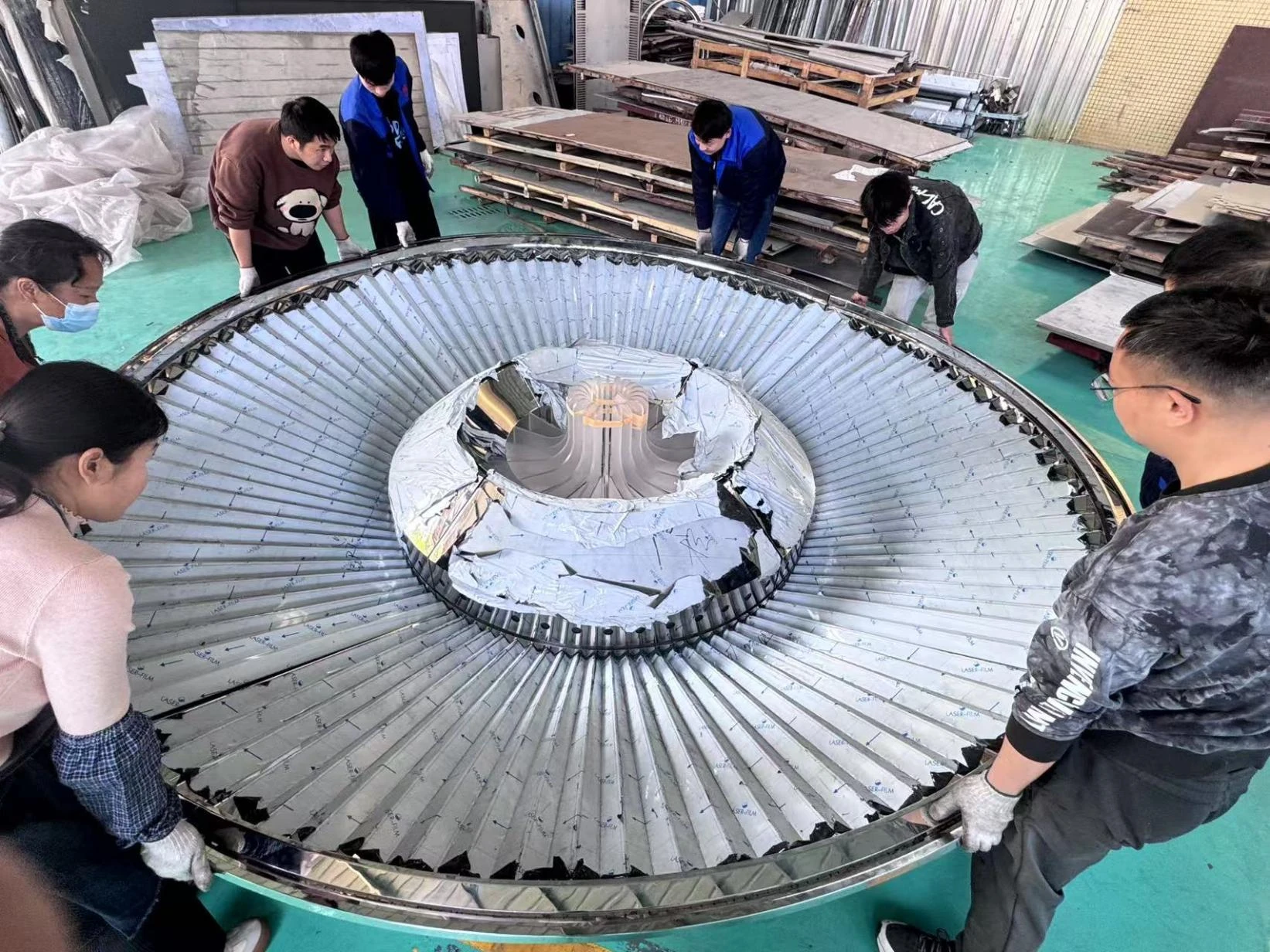 ALG team handling a large curved metal assembly in the workshop